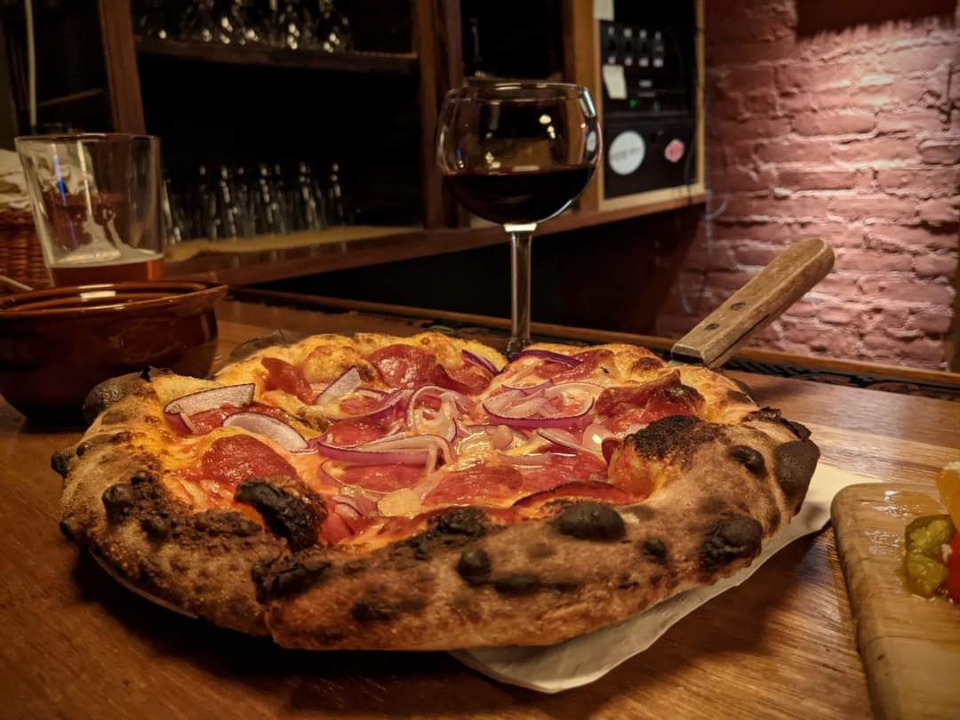 Pizza with red onions and pepperoni served with red wine